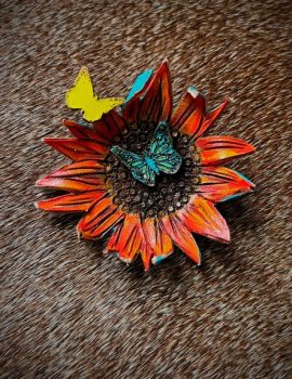 Sunflower pin with 2 butterflies painted in orange, brown and yellow with a second butterfly painted and decorated in turquoise green. Has a antique gold stick pin