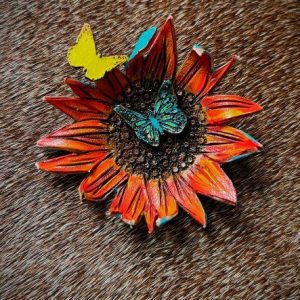 Sunflower pin with 2 butterflies painted in orange, brown and yellow with a second butterfly painted and decorated in turquoise green. Has a antique gold stick pin